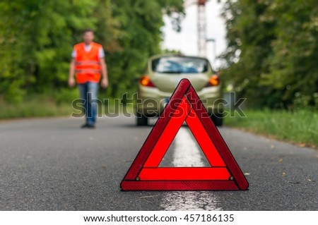 Broken car on the road and red warning triangle