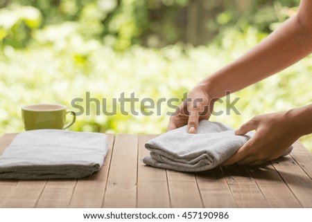 Close up woman hand folding clothes on wood table,Close up woman folding clothes into chest of drawers closeup.