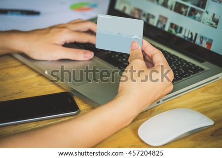 Woman's hands holding a credit card and using pc or laptop for online shopping.