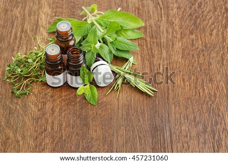 Dropper bottles and herbs on wooden background