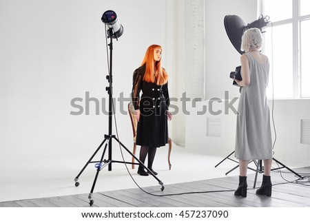 Girl fashion model and photographer are in the Studio on white background