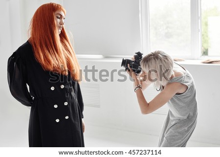 Girl photographer photographing fashion model in black color on white background in Studio