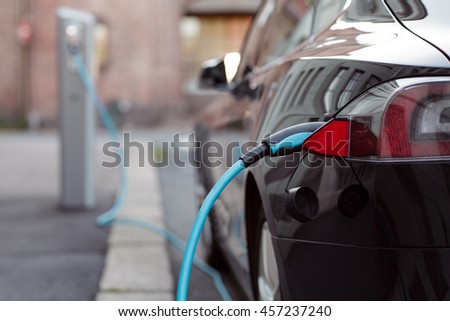 Back side of the car loading energy. Detail of the power supplier for charging of an electric car. Royalty-Free Stock Photo #457237240