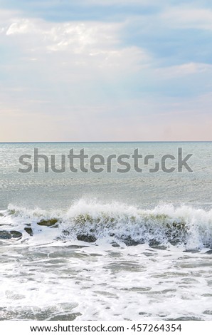 Waves and sea foam on the sea shore, morning light, sunny summer day. Calm water, splashing waves, blue and pink sky. Stillness inspiring picture.