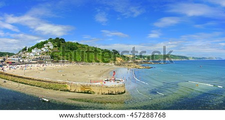 A Panorama view of Banjo Pier and Plaidy beach in summer with holiday makers enjoying the sea and surf, East Looe, Looe, Cornwall, England, UK  Royalty-Free Stock Photo #457288768