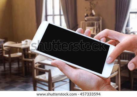 woman hand hold and touch screen smart phone, tablet,cellphone over blurred restaurant background.