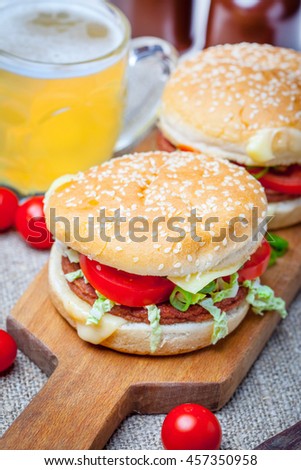 Homemade hamburger with fresh vegetables on wooden board.