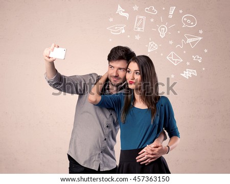 A young couple in love taking selfie with a mobile phone in the handsome guy's hand and drawn media communication icons above them, confused ideas concept