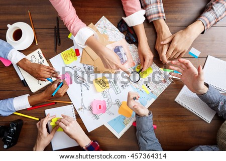 Picture of businessmen's hands on wooden table with documents and drafts