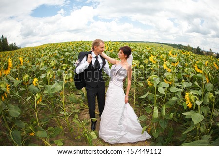 Rounded picture of happy wedding couple standing on the field of sunflowers