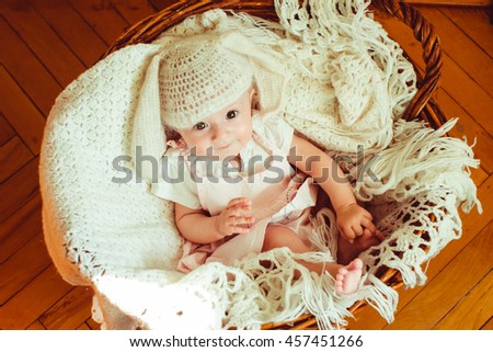 lovely newborn girl in a nice hat sitting in a wooden basket