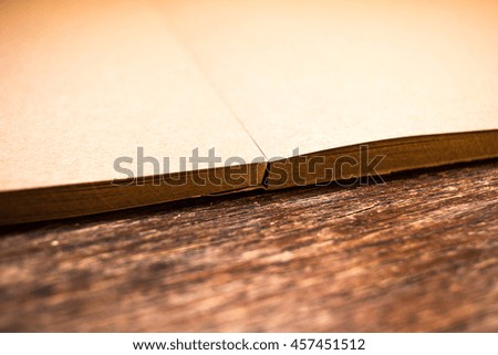 Old beige grained paper for painting on old grungy dark brown wooden table background close up. Soft focus