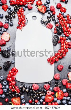 White cutting board and fresh summer berries on dark background, top view, fame