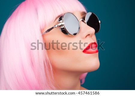 beautiful woman wearing colorful wig and silver sunglasses against blue background