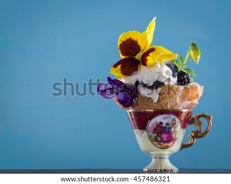 Luxury dessert with pansies in the authentic porcelain coffee cup.