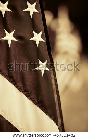 Antique editing applied to this shallow depth of field photo of the American flag folded on the flag pole. Blurred out flags in the background. Vertical format with copy space