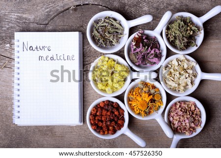 Nature medicine . Herbs & notebook on wooden background .