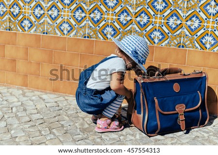 Child with briefcase on city road sunny outdoors background
