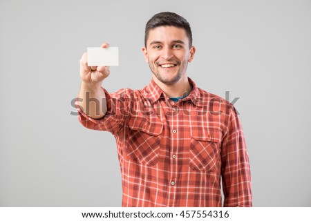 Young man holding and showing blank business card isolated on gray background