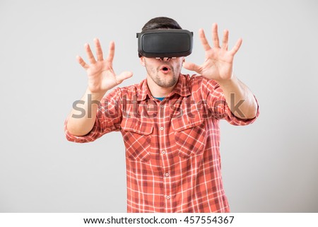 Man with virtual reality glasses showing gesture isolated on a gray background