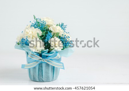 close up of beautiful Jasmine flower bouquet with blue ribbon bow on white wooden background - Jasmine is the symbol of Mother's Day in Thailand. Royalty-Free Stock Photo #457621054