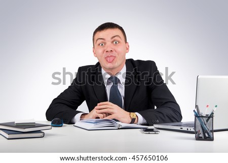 Office, finances, internet, business, success concept-Businessman showing tongue on gray background