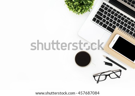 Modern white office desk table with laptop computer, smartphone with black screen over a notebook and cup of coffee. Top view with copy space, flat lay. Royalty-Free Stock Photo #457687084