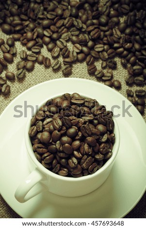 Coffee beans and coffee in cup on burlap. Selective focus. Toned.