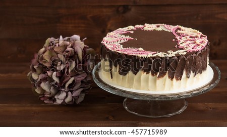 Cake with mehendi patterns on the glass stand. Wooden background.