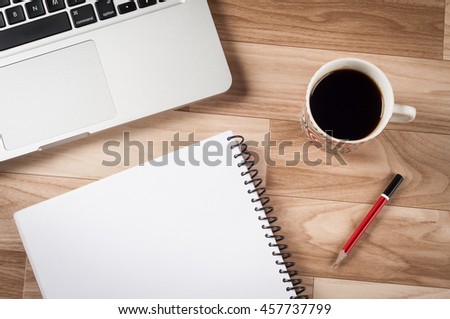 Top view of office table workplace with black coffee, laptop, notepad, pencil.   