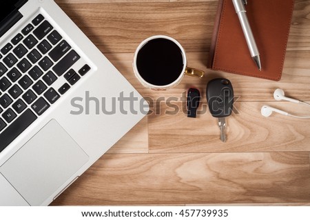 Office desk table top view no people with laptop, notepad, pen, pen drive, car keys, black coffee cup and earphone.The office table made by wood and beautiful shiny look. Royalty-Free Stock Photo #457739935