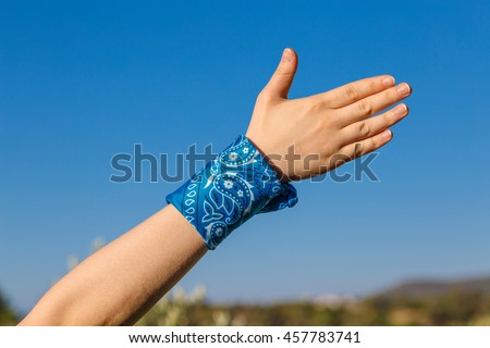 female hand with a blue bandana with hand on nature background (bunch of fives)