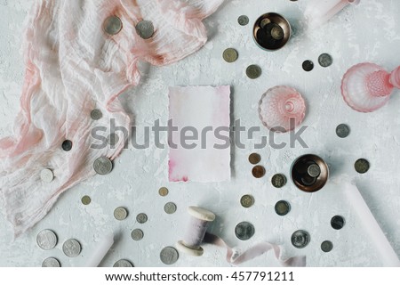 pink empty paper blank with coins, candlesticks, and pink textile on concrete background. Flat lay, top view