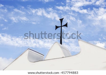 Black metal cross on the church's gates in a blue sky background