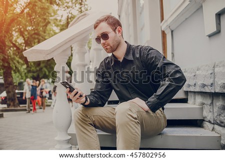 A guy in a nice town, walking, listening to music and taking pictures themselves on the phone