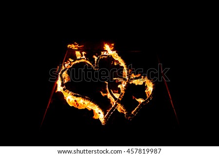 Burning heart - heart-shaped ring of fire and orange flames. Two hearts on fire on isolated black background