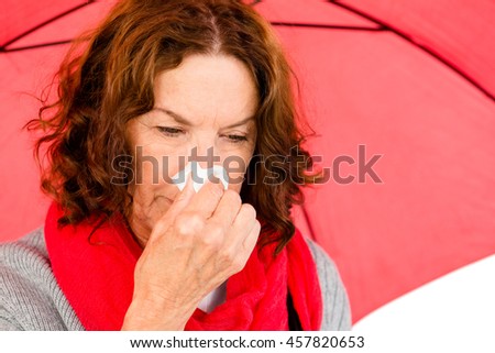 Close-up of mature woman suffering from cold while holding umbrella