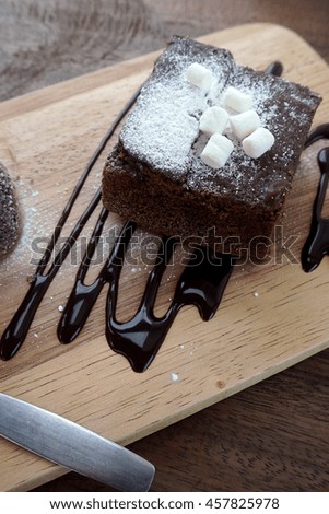 Delicious brownie with dark chocolate sauce on a wooden board