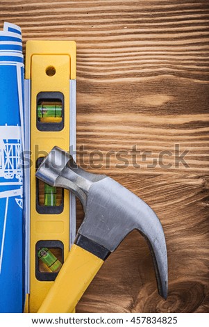 Construction level blue blueprint claw hammer on vintage wood board.
