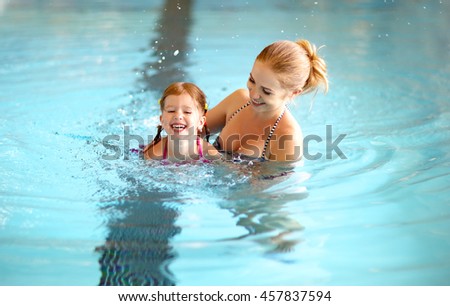 healthy family mother teaching child daughter swimming pool