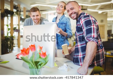 Portrait of smiling business people standing at desk in creative office