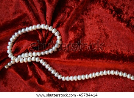 Necklace of white pearls on a terracotta velvet as background