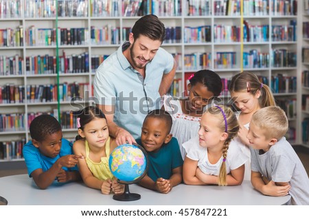 Pupils and teacher looking at globe in library at elementary school Royalty-Free Stock Photo #457847221