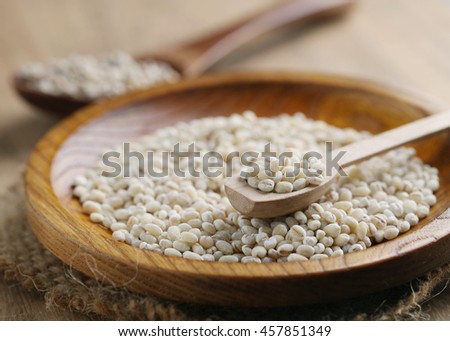 Pearl barley grain seeds on wooden plate.