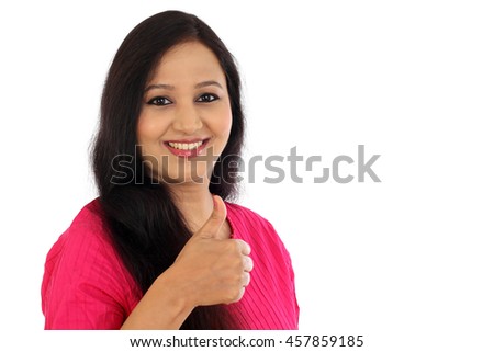 Happy young woman making thumbs up gesture against white background