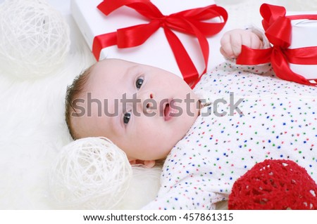 smiling baby age of 3 months lying among gifts