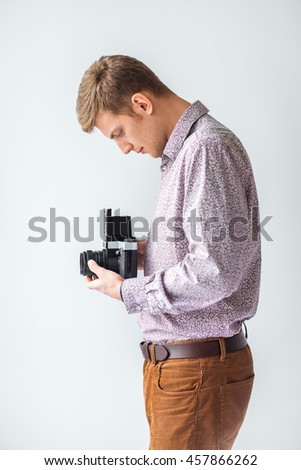 Portrait of handsome man with old medium format camera in studio