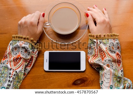 Closeup on hand using mobile smart phone, wooden desk background, mock up flat lay