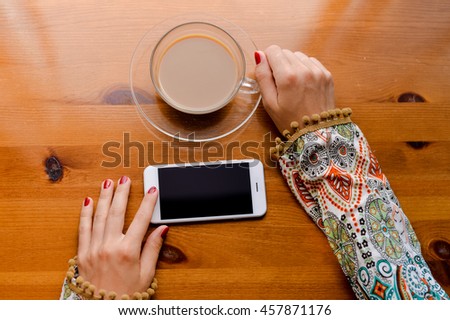 Closeup on hand using mobile smart phone, wooden desk background, mock up flat lay