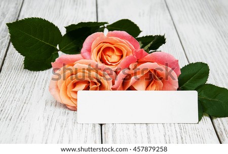 Pink roses and greeting card on a old wooden background